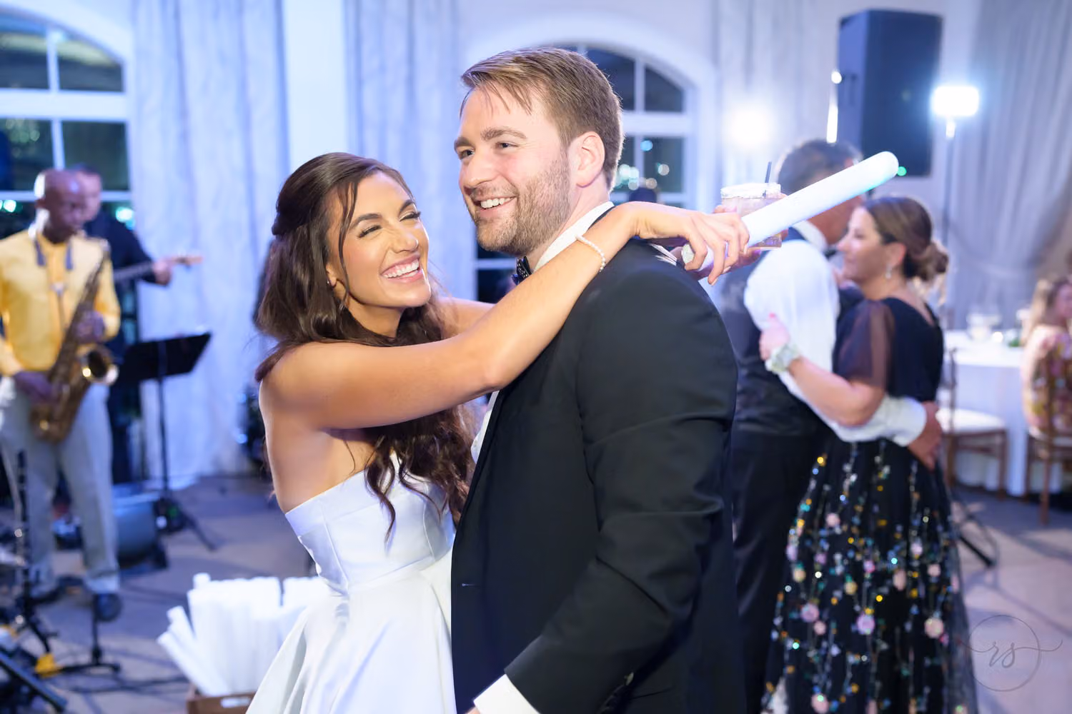 Bride and groom laughing and dancing with guests as a saxophone player performs at the reception at 21 Main Events