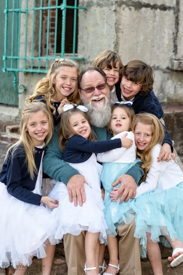 Grandfather hugged by his grandkids by the teal window grates at Atalaya Castle