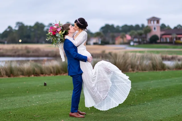 Groom lifting the bride into the air for a kiss on the golf course at Grande Dunes in Myrtle Beach