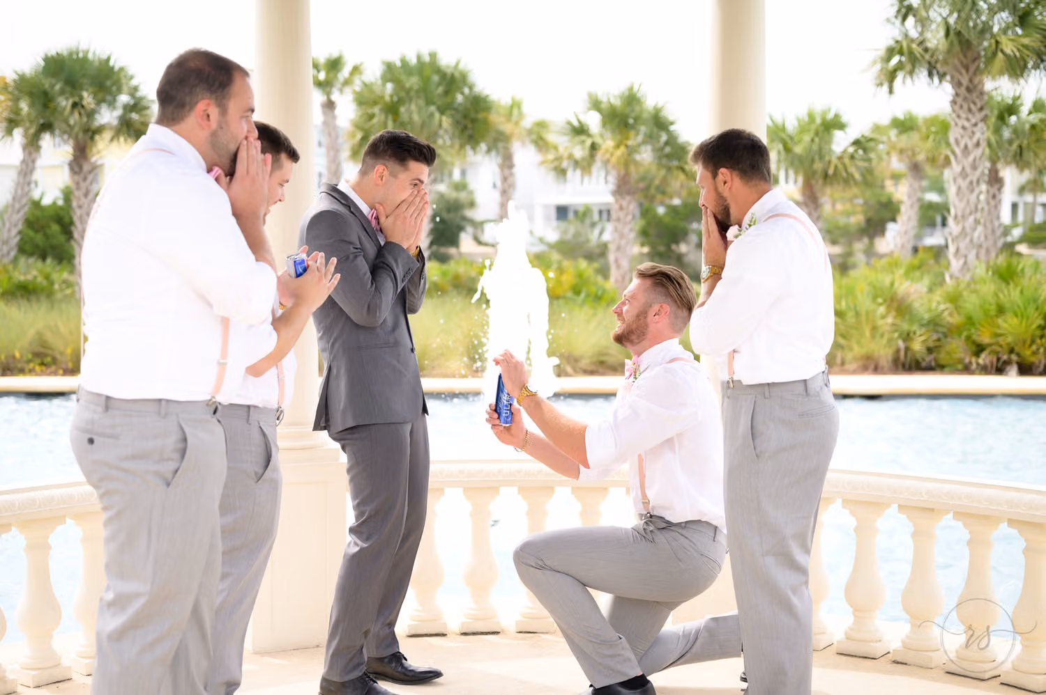 Groomsman kneeling to offer the groom a can of beer as the other groomsmen laugh at 21 Main Events at North Beach