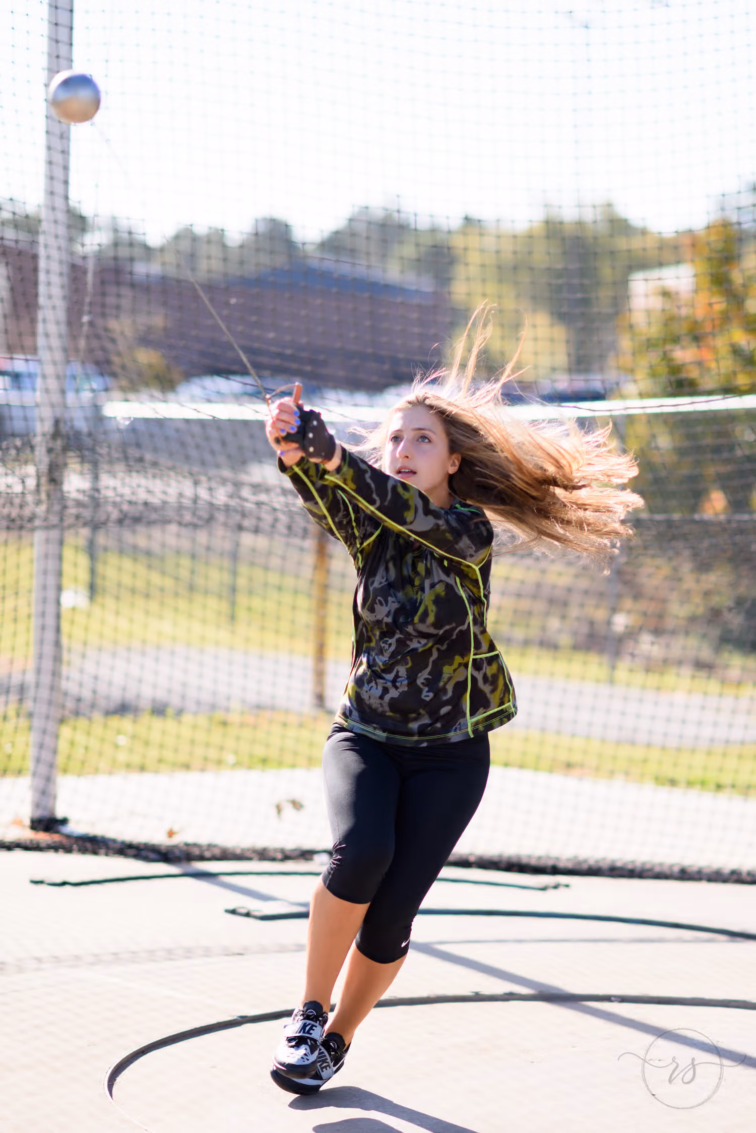 Senior athlete mid-spin with her hair flying as she releases the hammer at Myrtle Beach High School