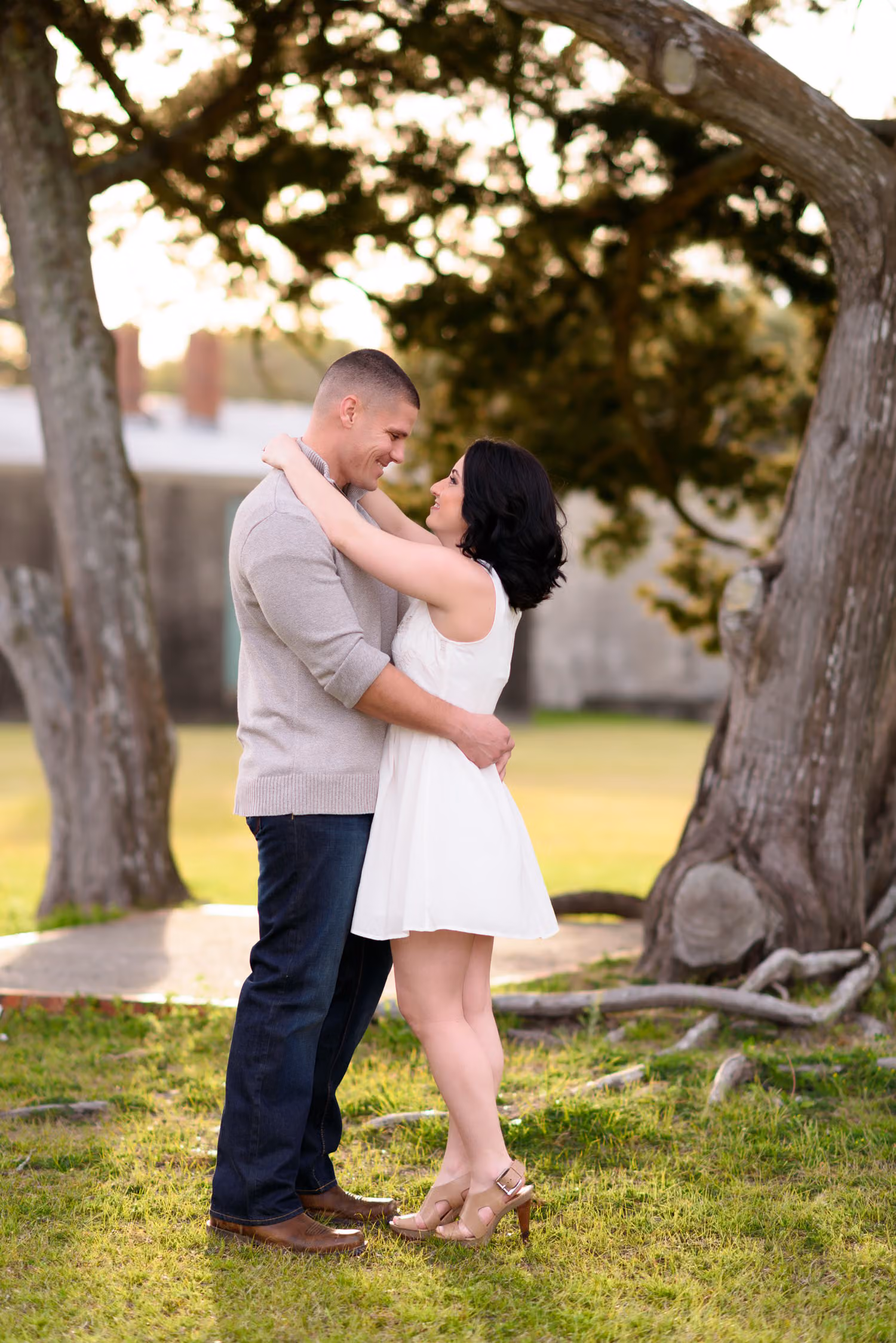 Couple embracing under an oak tree with the walls of Atalaya Castle behind them at Huntington Beach State Park