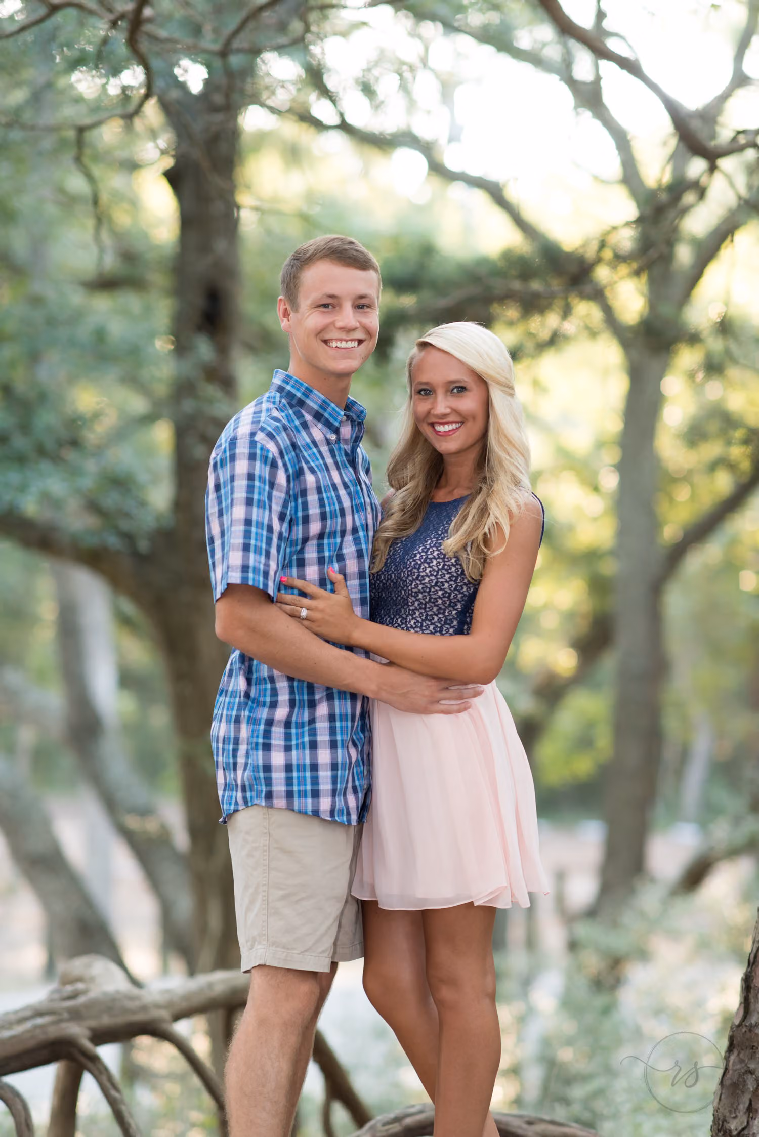 Smiling couple hugging among twisted trees with sunlight coming through from behind at Myrtle Beach State Park