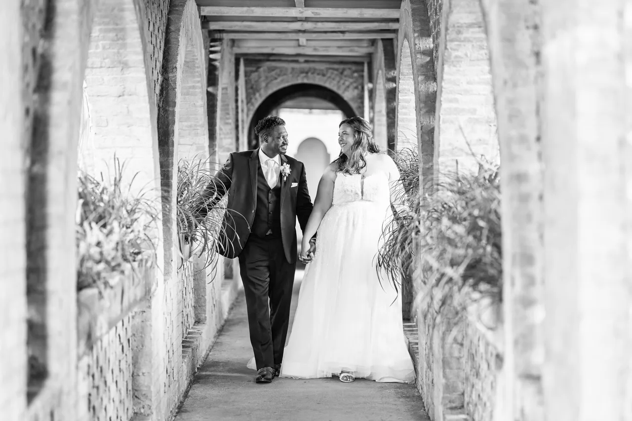 Jessica and her groom walking hand in hand through the castle arcade in black and white at Atalaya Castle