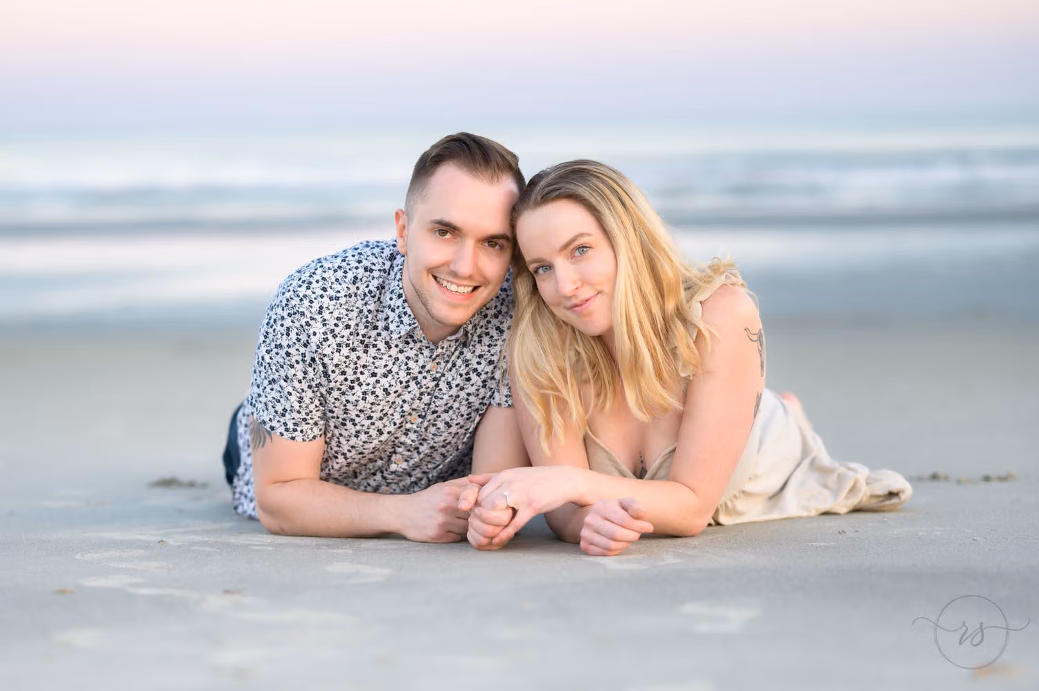 Smiling couple lying on their stomachs in the sand by the ocean at Inlet Point Plantation