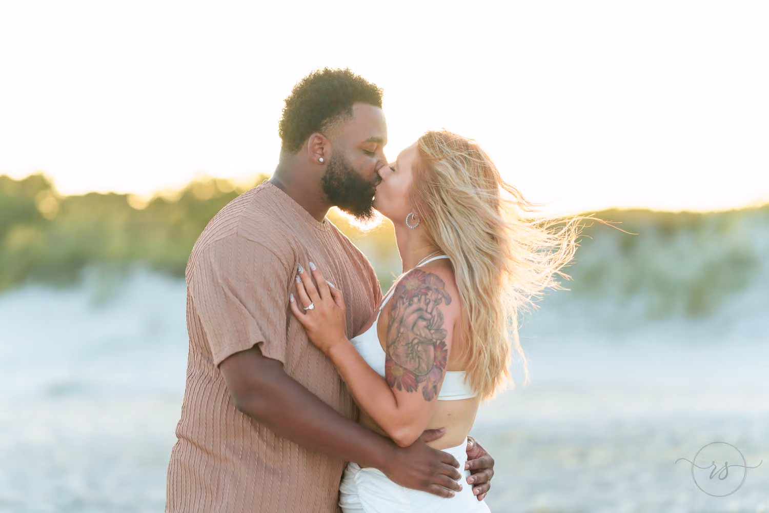 Couple kissing in soft backlight with the dunes glowing behind them at Huntington Beach State Park