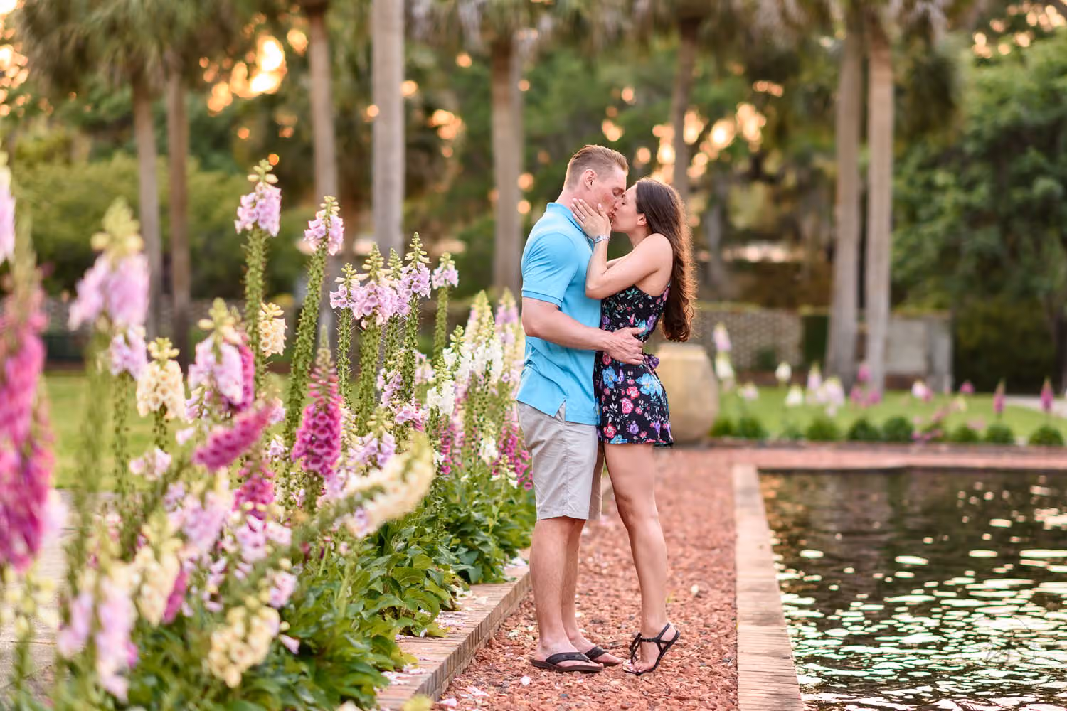 Couple kissing beside a reflecting pool lined with pink foxgloves in the Palmetto Garden at Brookgreen Gardens