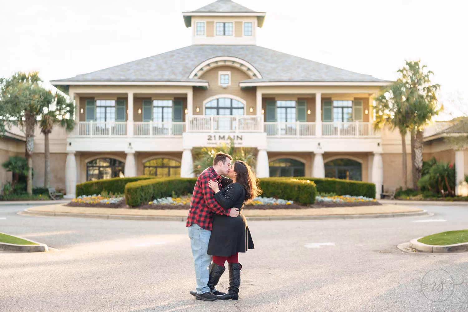 Couple kissing on the drive in front of a large white clubhouse with a cupola at 21 Main Events