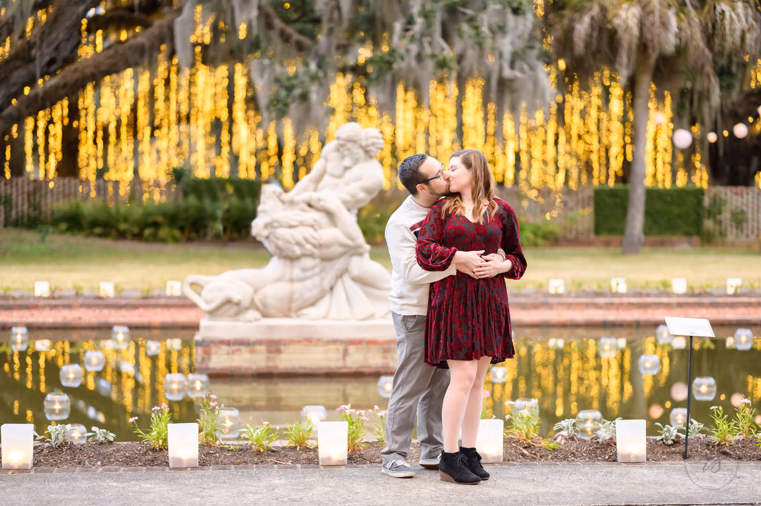 Couple kissing beside the Samson and the Lion sculpture with lights hanging from the oaks at Brookgreen Gardens