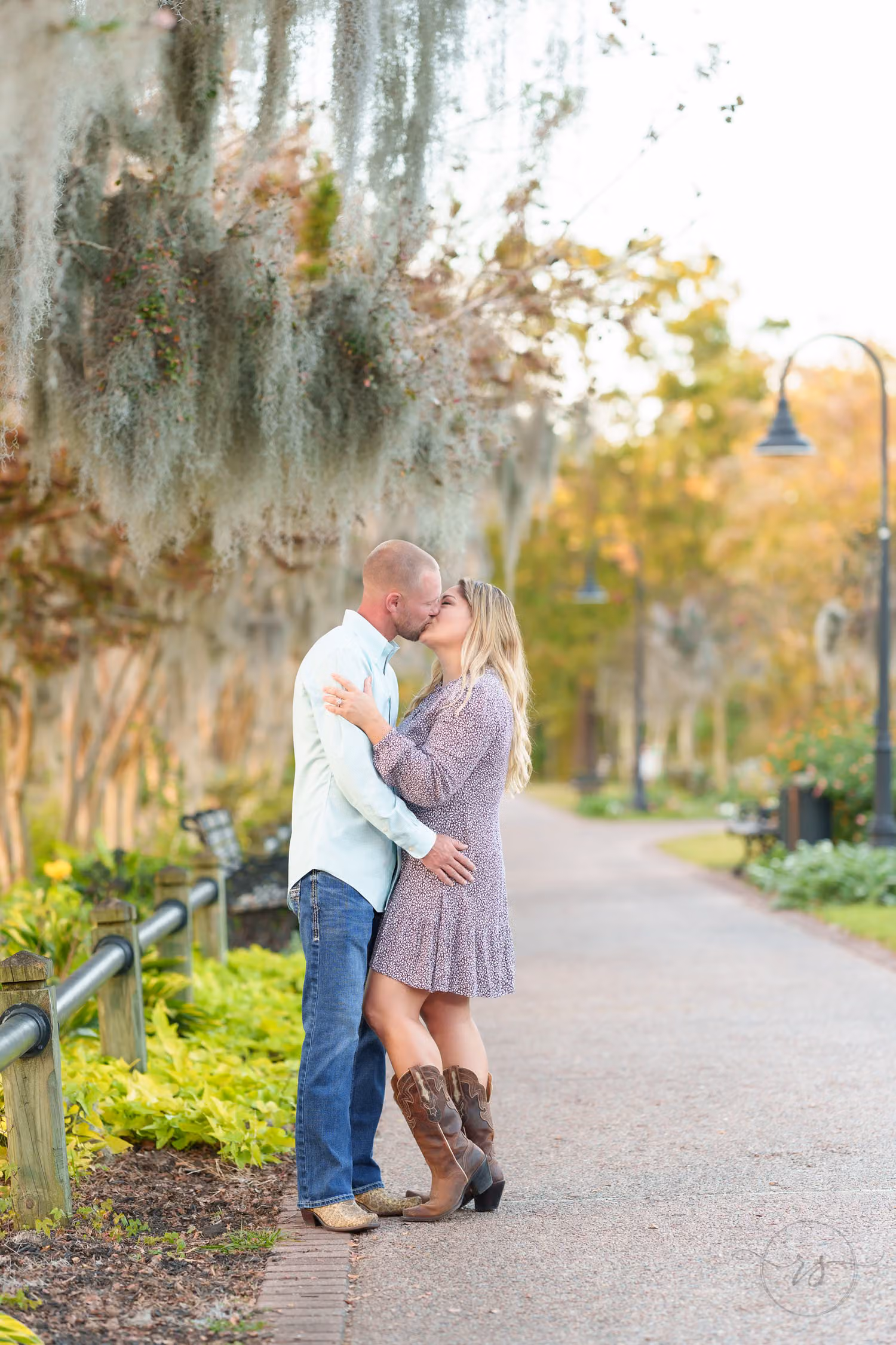 Couple kissing on a curving path under trees hung with Spanish moss at the Conway Riverwalk