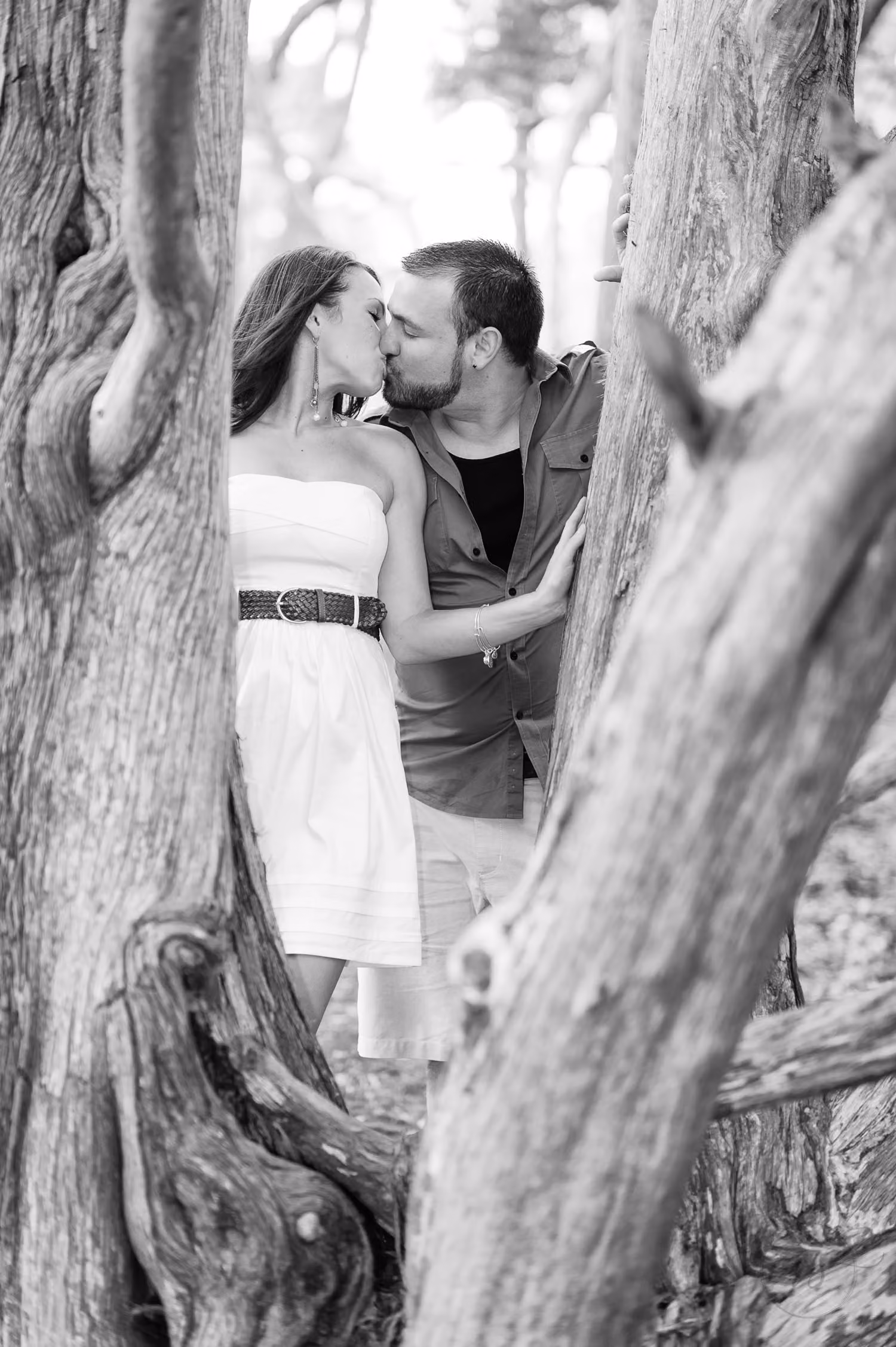 Black and white photo of a couple kissing between two twisted oak trunks at Myrtle Beach State Park