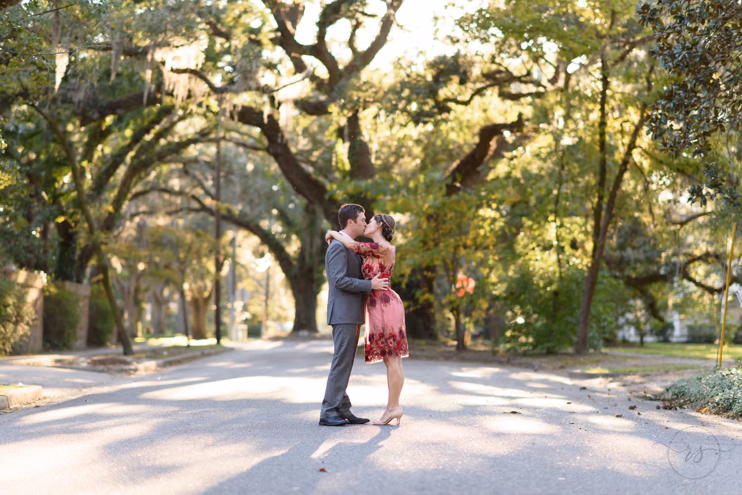 Couple kissing in the middle of a quiet street shaded by big oak trees on Oak Street in Conway