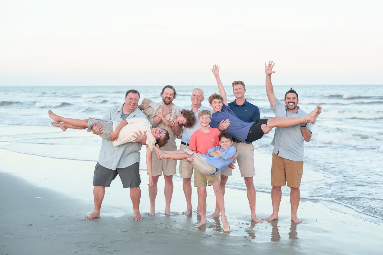 Kristin's family clowning around at the water's edge, lifting the kids and waving