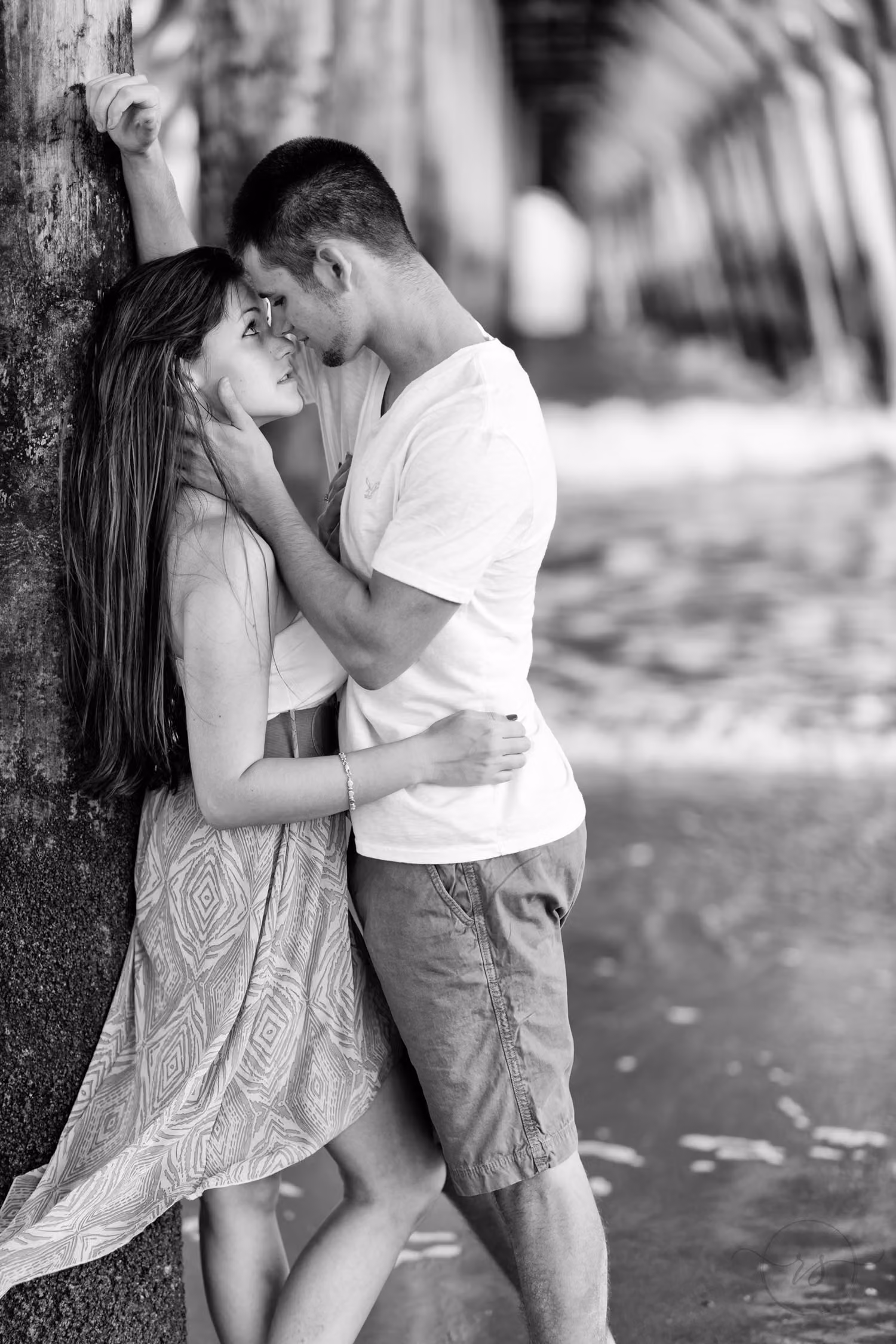 Black and white photo of a couple leaning against a pier piling, about to kiss, in Myrtle Beach