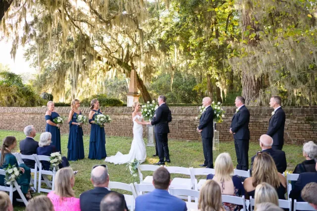 Outdoor ceremony under moss-draped oaks in the late sun at Reserve Harbor Yacht Club