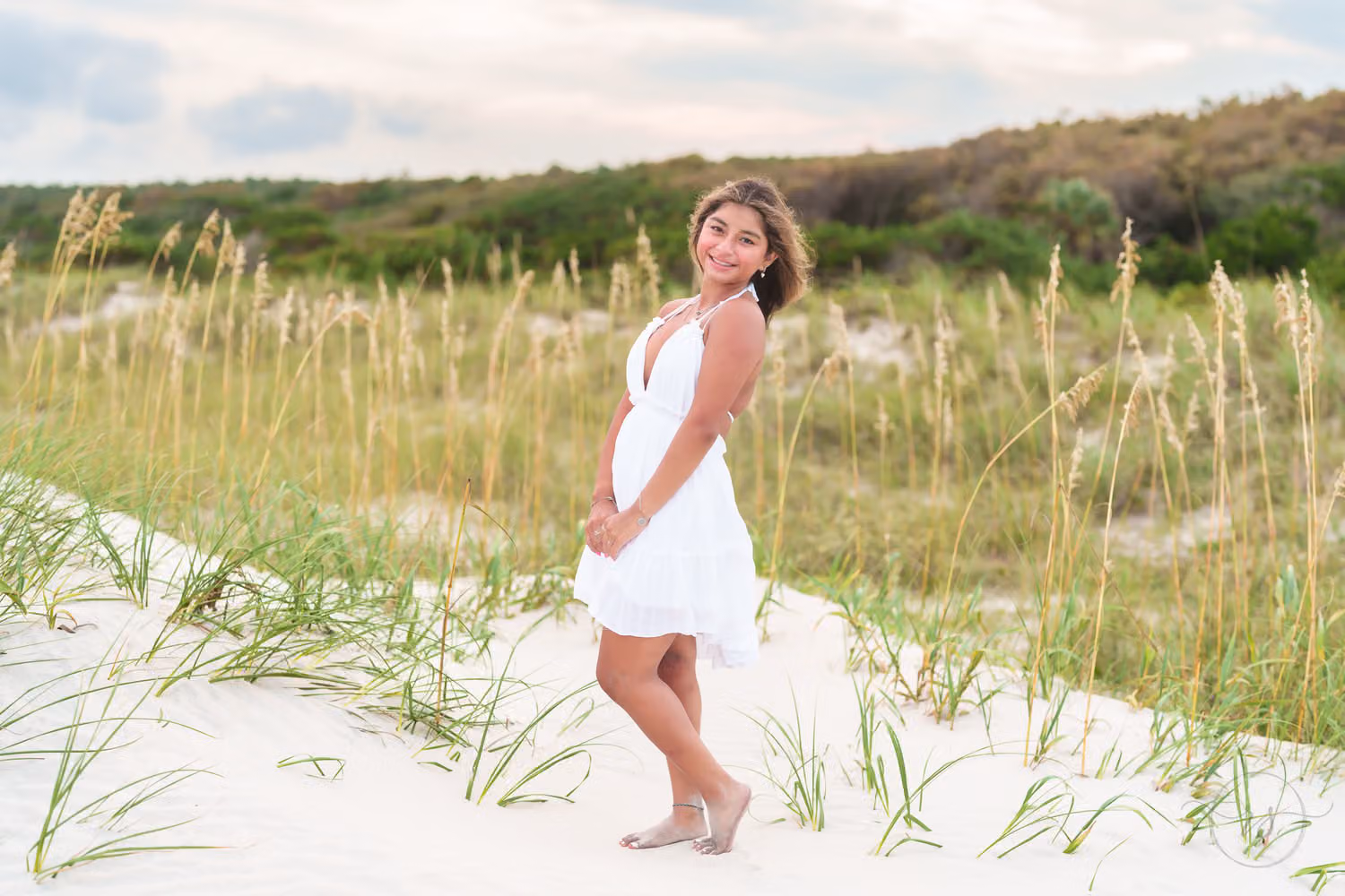 Senior in a white dress standing on the dunes among tall sea oats at Huntington Beach State Park