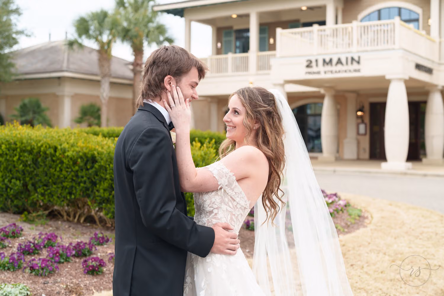 Groom holding the bride's face as they smile at each other outside 21 Main Prime Steakhouse in North Myrtle Beach