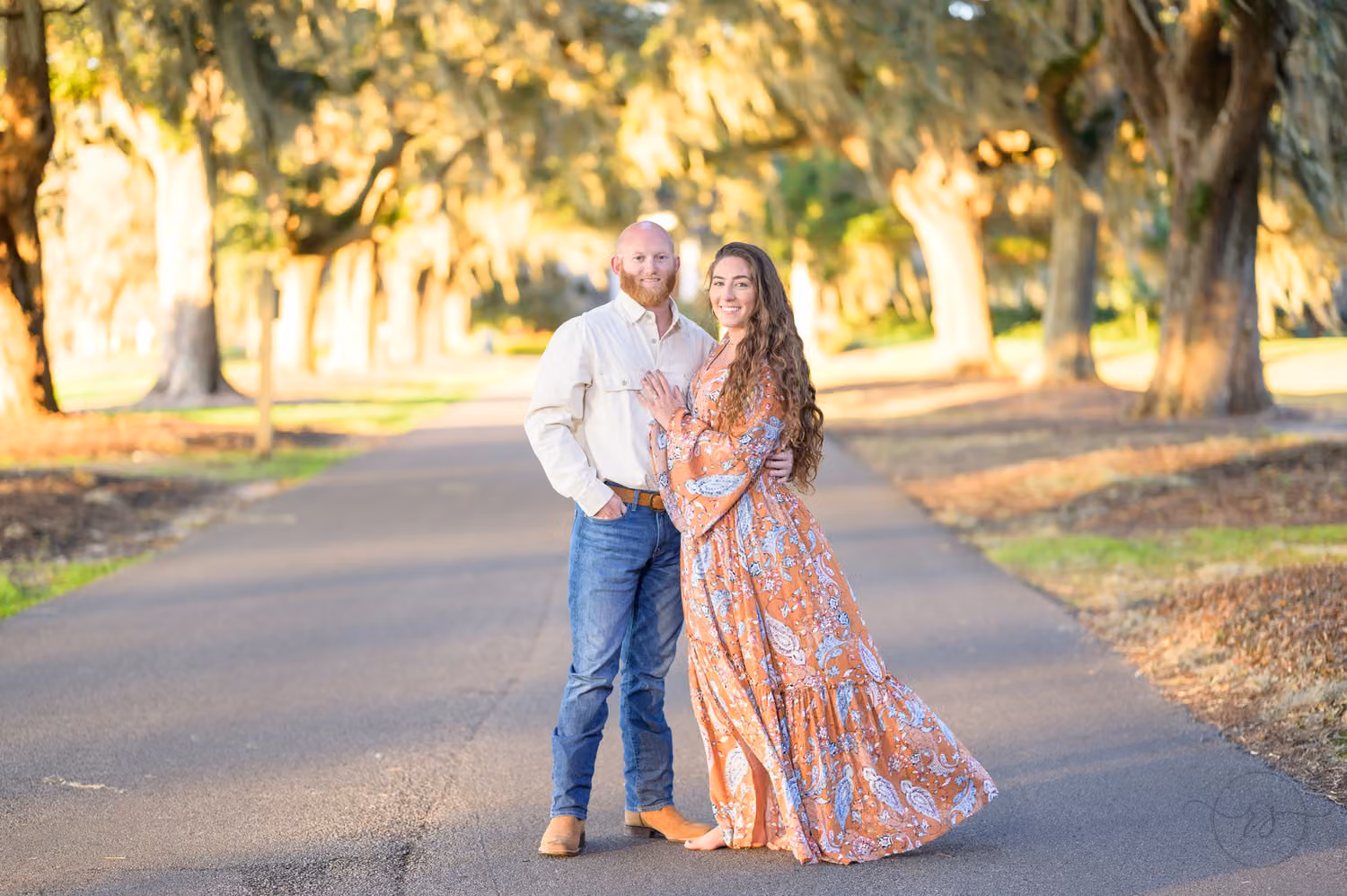 Couple standing on a road under an avenue of oaks draped in Spanish moss at Caledonia Golf & Fish Club
