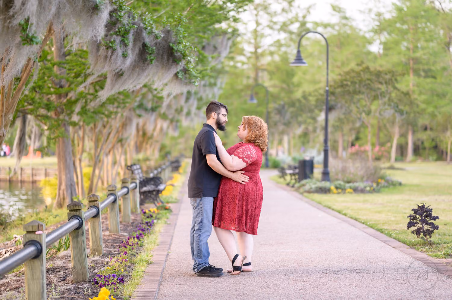 Couple hugging on a brick path lined with mossy trees and old streetlights along the Conway Riverwalk