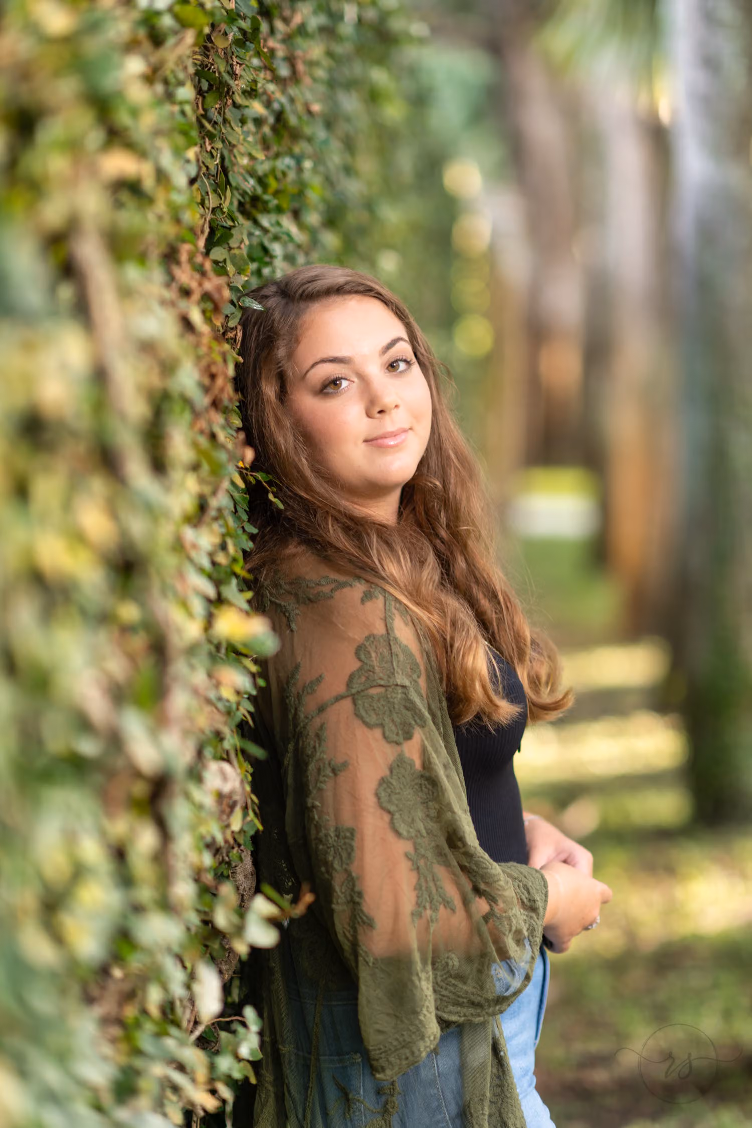 Senior in an olive lace kimono leaning back against the ivy wall at Atalaya Castle