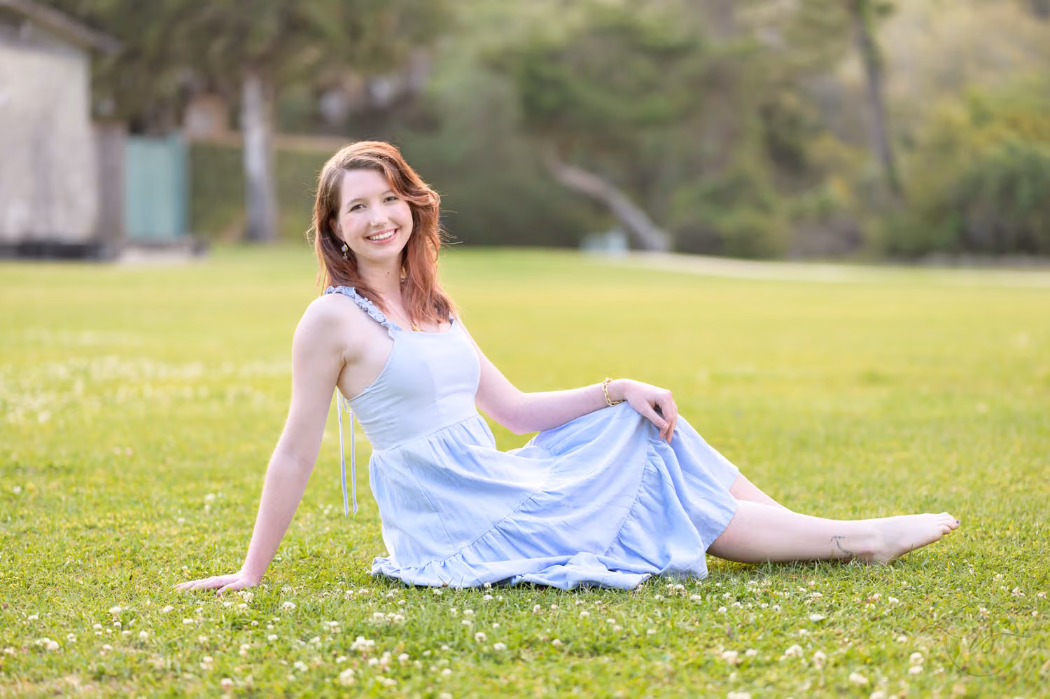 Senior girl in a light blue dress reclining on the grass near Atalaya Castle at Huntington Beach State Park