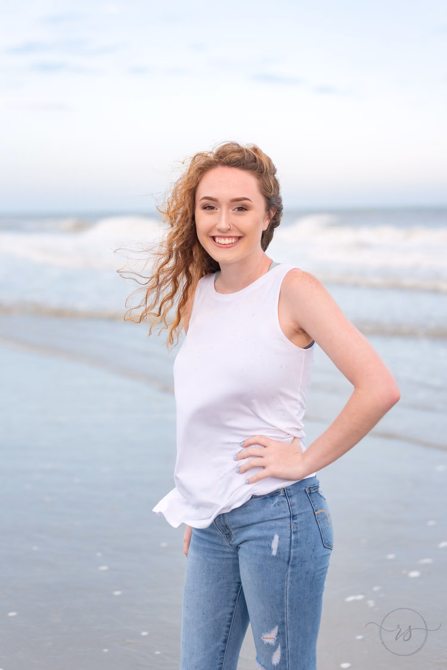Red-haired senior with windblown hair and a hand on her hip on the beach at Grande Dunes in Myrtle Beach