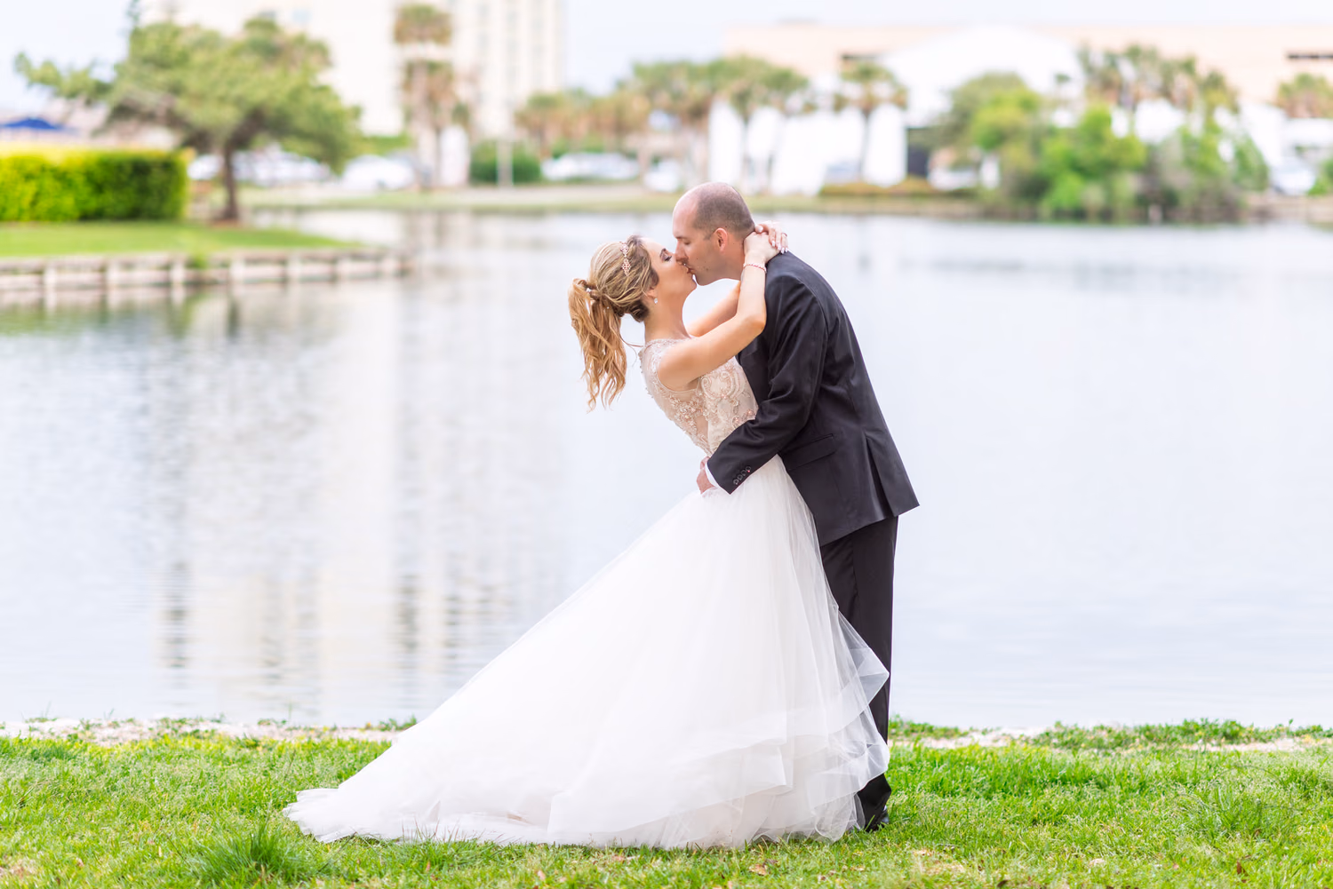 Groom leaning back bride for a kiss by the lake - Kingston Resorts Myrtle Beach