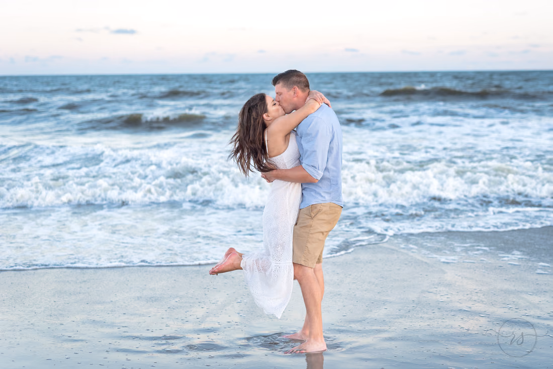 Couple kiss in the surf after a surprise proposal at Holden Beach, NC