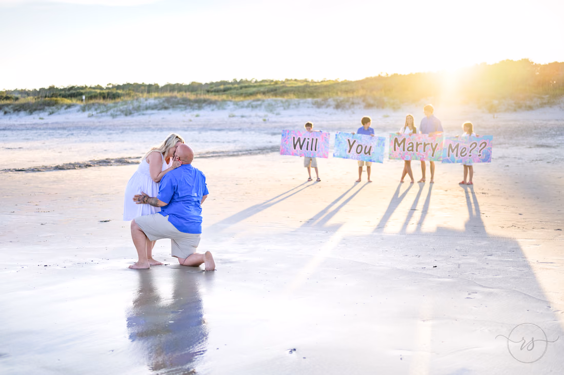 Kiss with the kids holding the signs in the background - Huntington Beach State Park