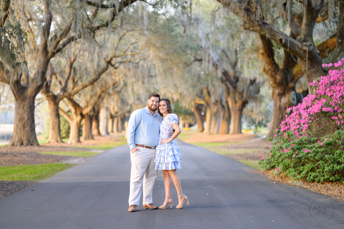 Couple standing close on the road beneath an avenue of mossy oaks at Caledonia Golf and Fish Club