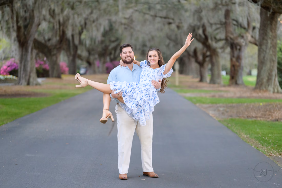 He carries her in his arms as she throws one arm up under the oaks at Caledonia Golf and Fish Club