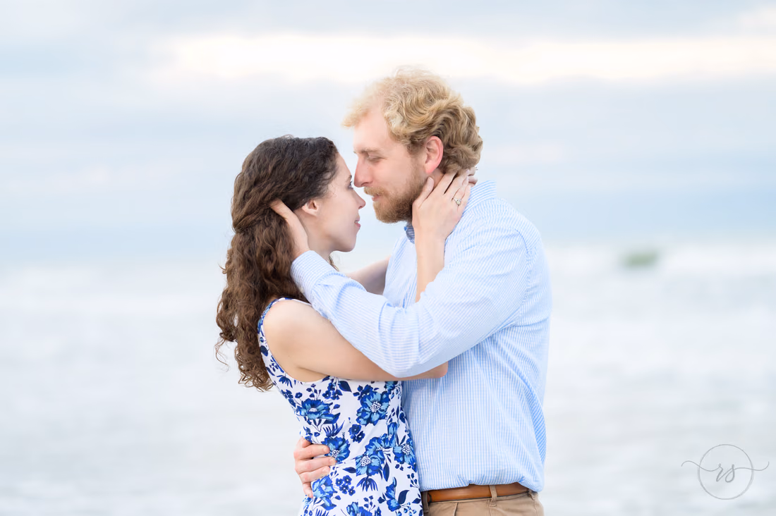 Pulling each other in for a kiss on a cloudy day by the ocean - Huntington Beach State Park