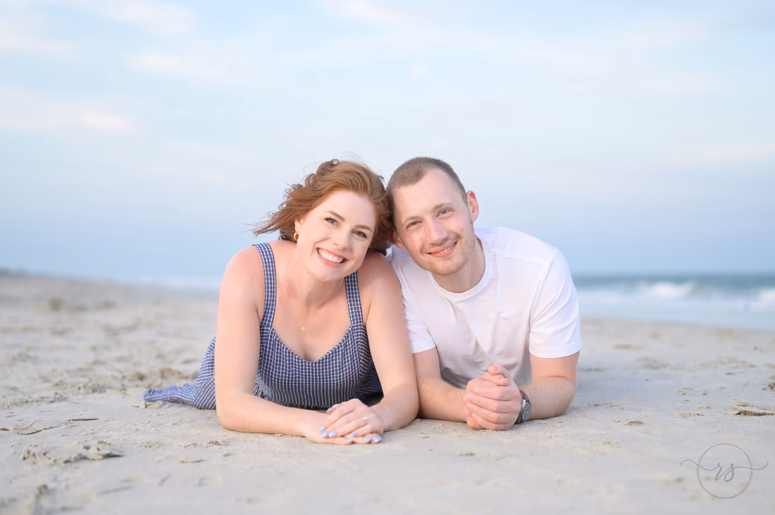 Couple lying on the sand smiling at the camera - Huntington Beach State Park