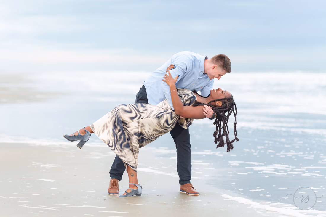 He dips her back and smiles at the water's edge - Huntington Beach State Park