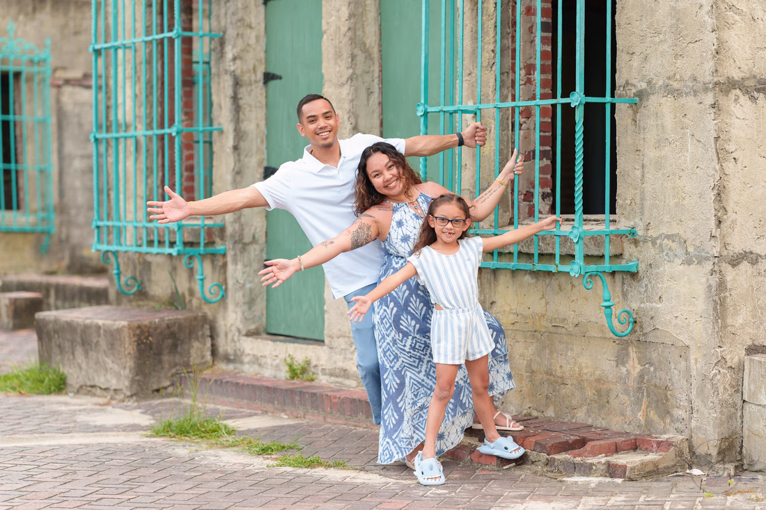 Family with arms out by the green doors of Atalaya Castle - Huntington Beach State Park
