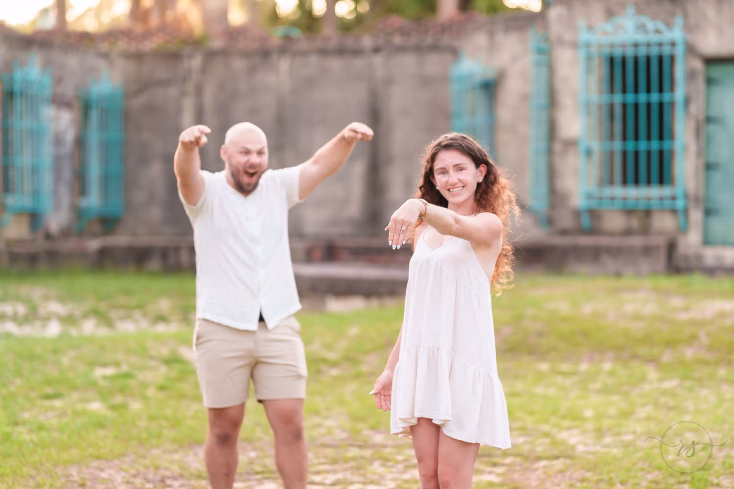Couple laughing and pointing excitedly in front of the castle wall with turquoise windows at Huntington Beach State Park