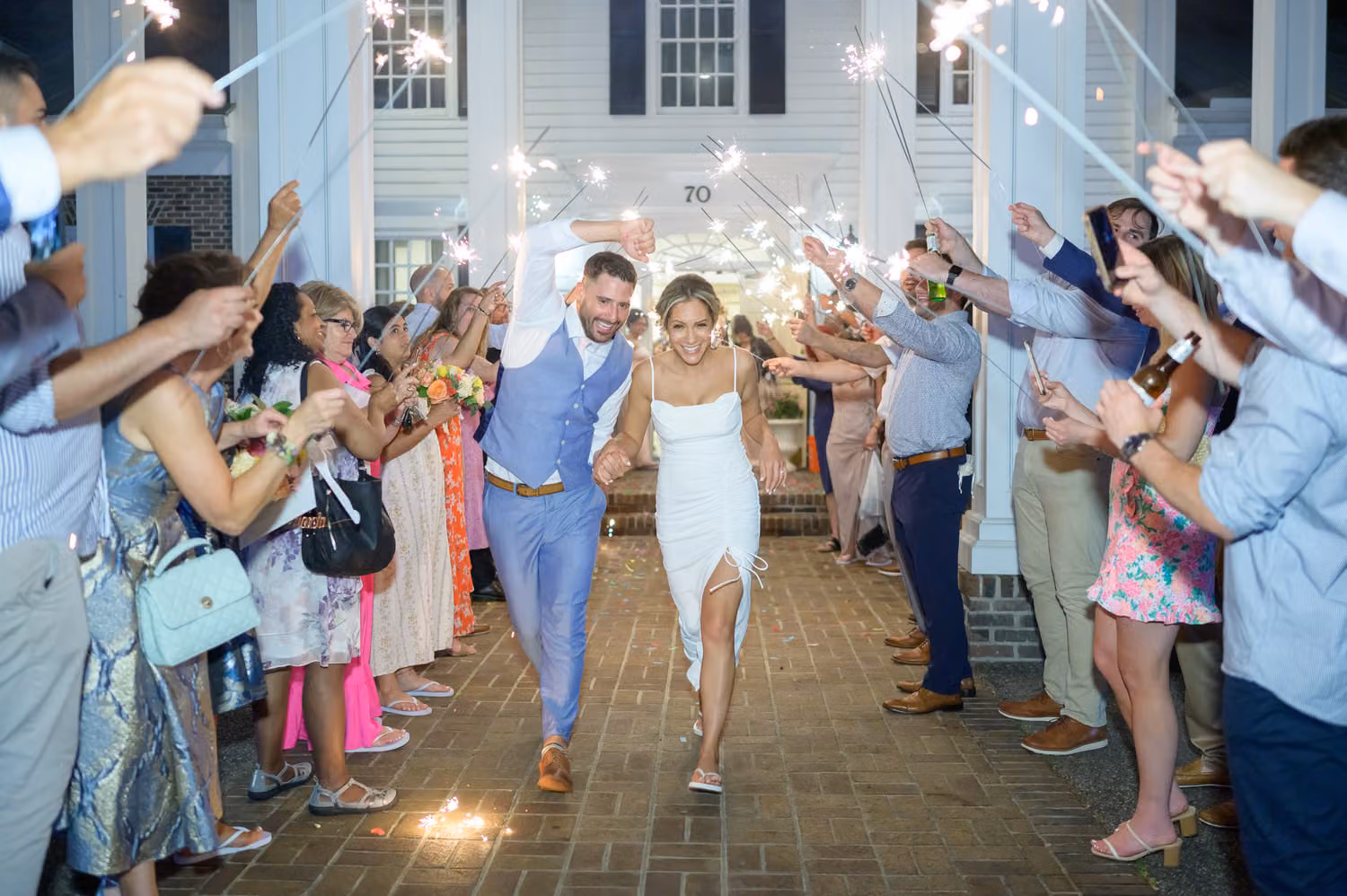 Bride and groom in a blue vest running through a tunnel of guests with sparklers at Pawleys Plantation Golf & Country Club
