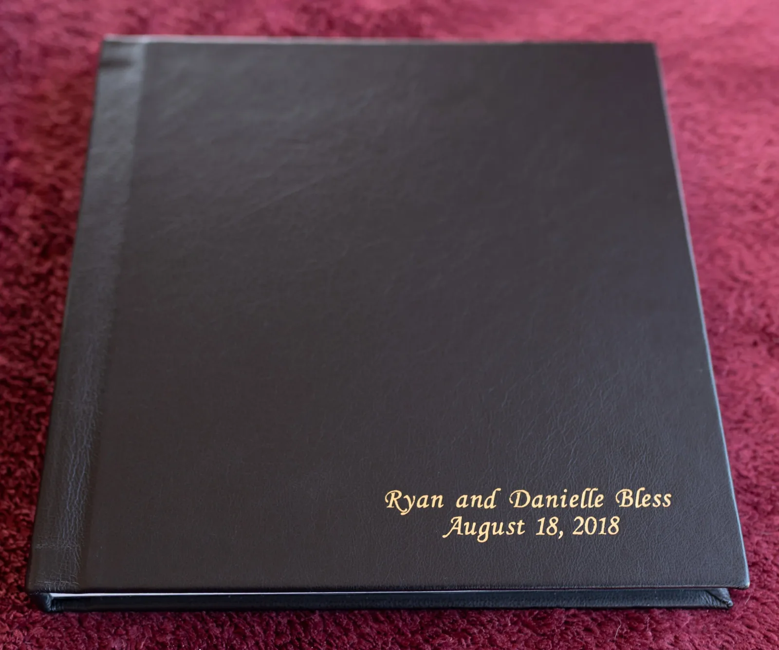 Standard wedding album with a dark leather cover and a gold-stamped couple name and wedding date