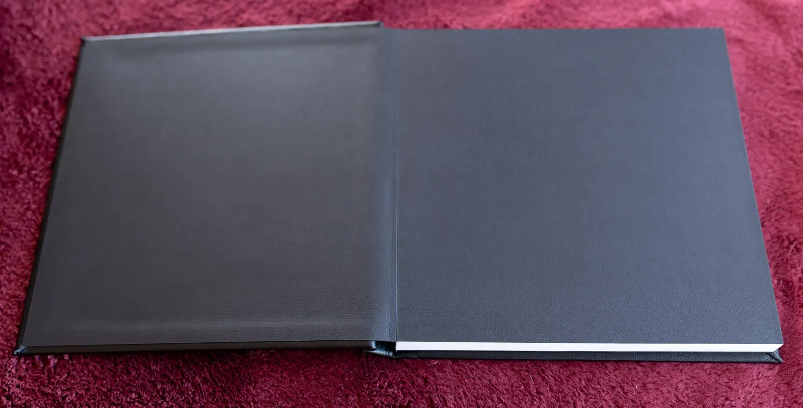 Standard wedding album laid open face down, showing the black leather front and back covers