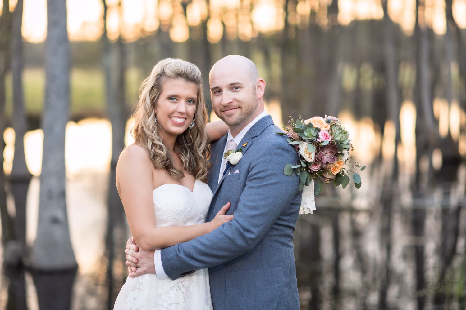 Bride and groom smiling cheek to cheek as sunset glows through the trees on the water at Wildhorse at Parker Farms
