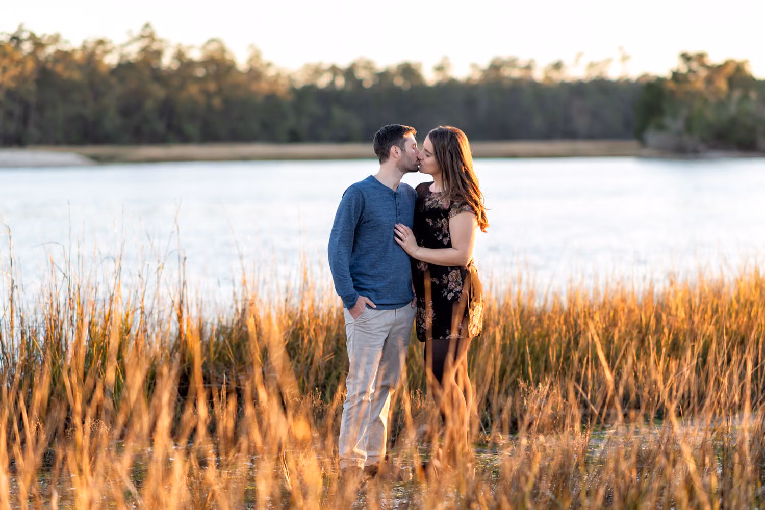 Couple kissing in golden marsh grass by the water at sunset at Vereen Memorial Gardens