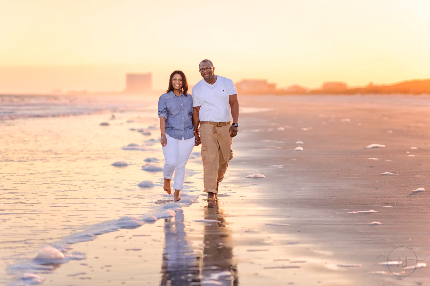 Couple walking hand in hand along the wet sand reflecting a golden winter sunset at Myrtle Beach State Park