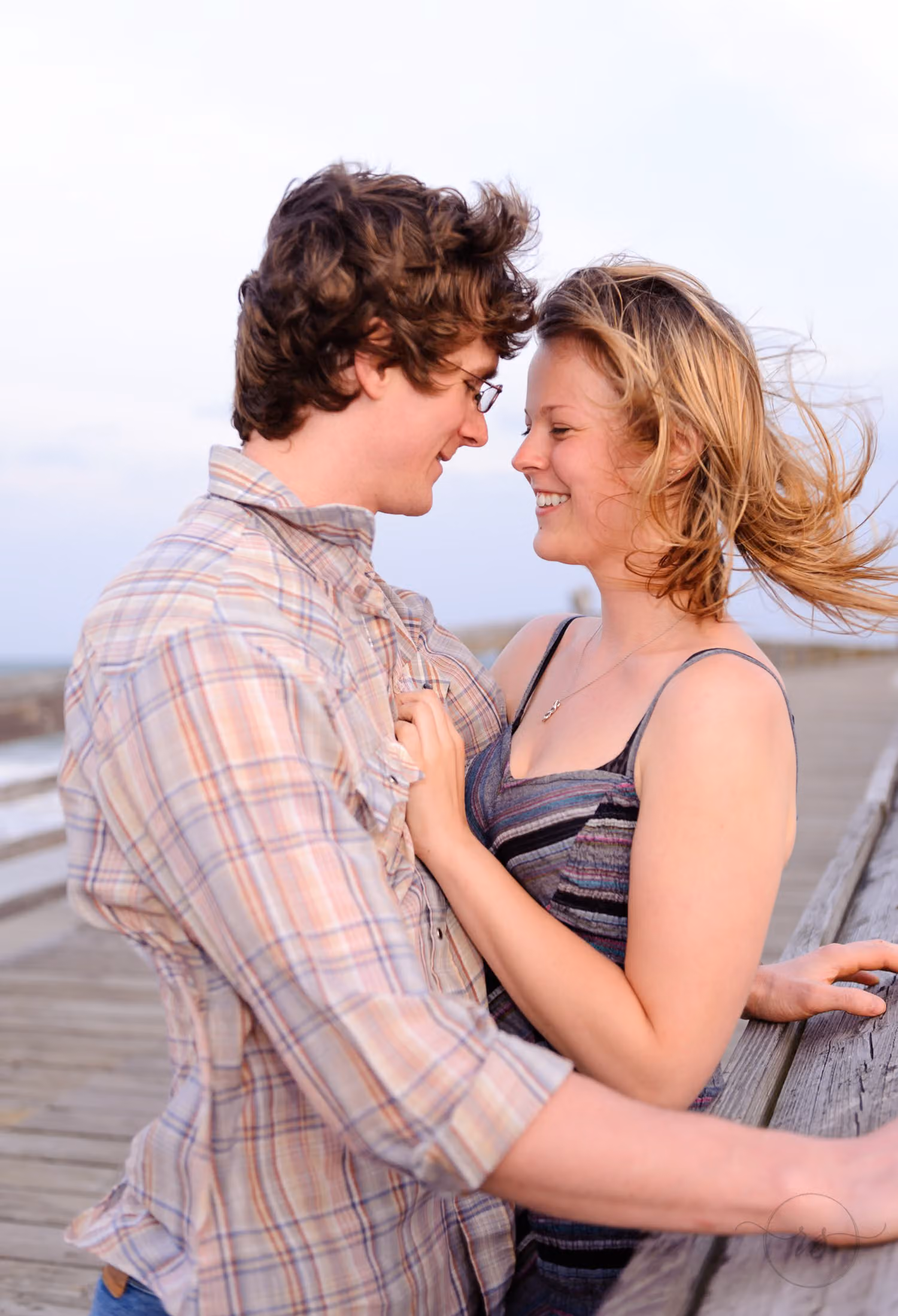 Couple smiling at each other on the pier as the wind blows her hair at Myrtle Beach State Park