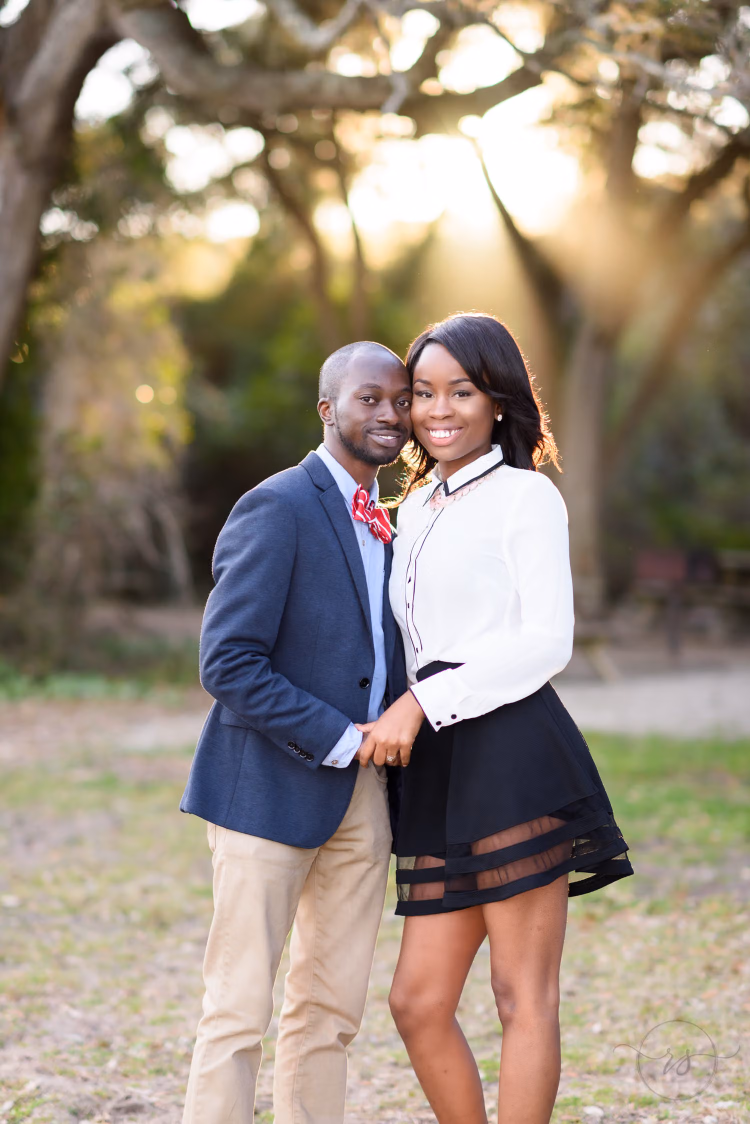 Couple standing close in a clearing with winter sunlight shining through the trees at Myrtle Beach State Park