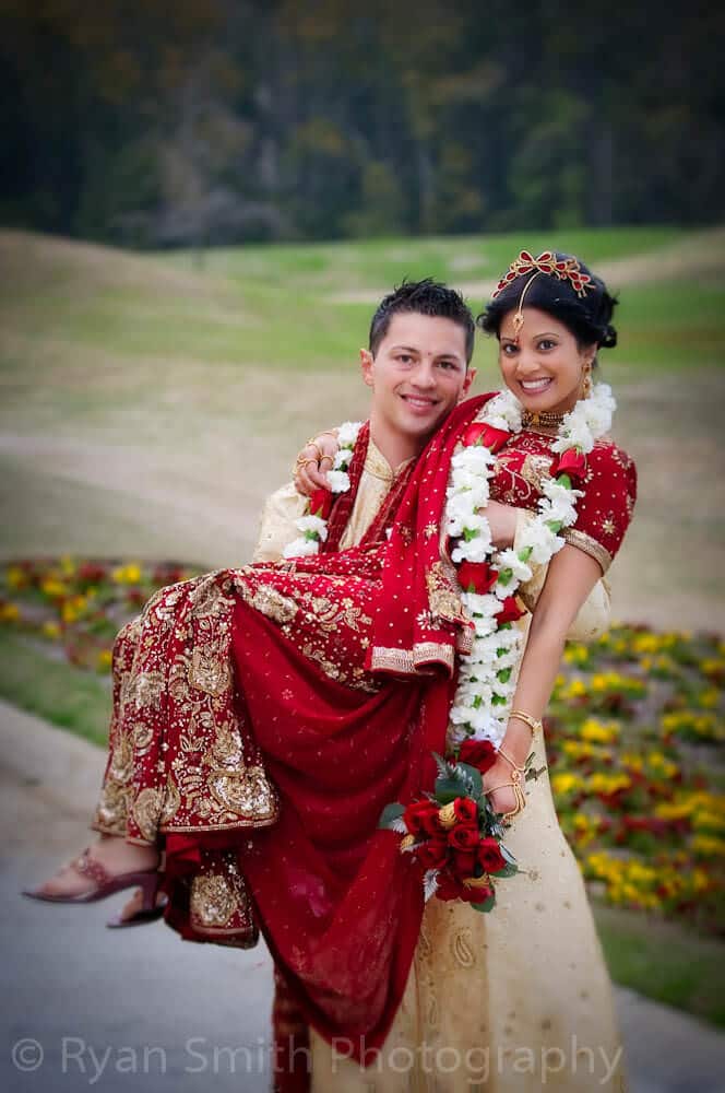 Groom lifting up bride in Indian wedding dress