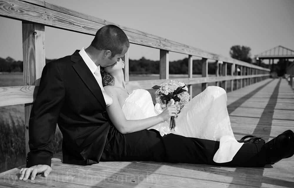 Bride and groom laying together on a pier, gritty black and white, ocean isle beach