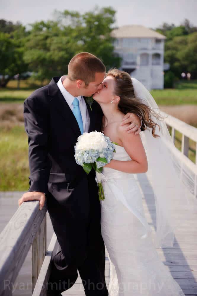 Bride and groom kissing on the windy pier, ocean isle beach