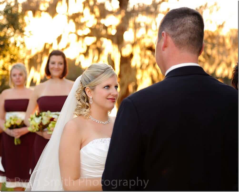 Bride smiling at groom during ceremony - Wachesaw Plantation
