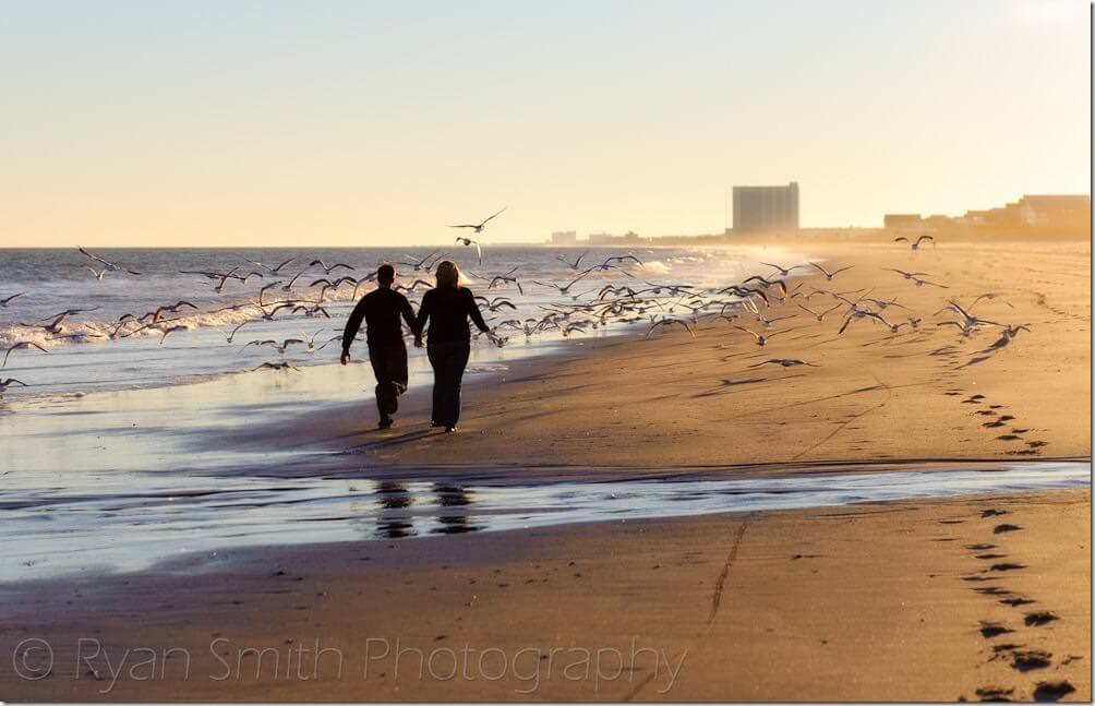 Couple running toward seagulls flying into the air - Myrtle Beach