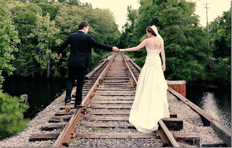 Bride and groom walking down train tracks together - Conway River Walk